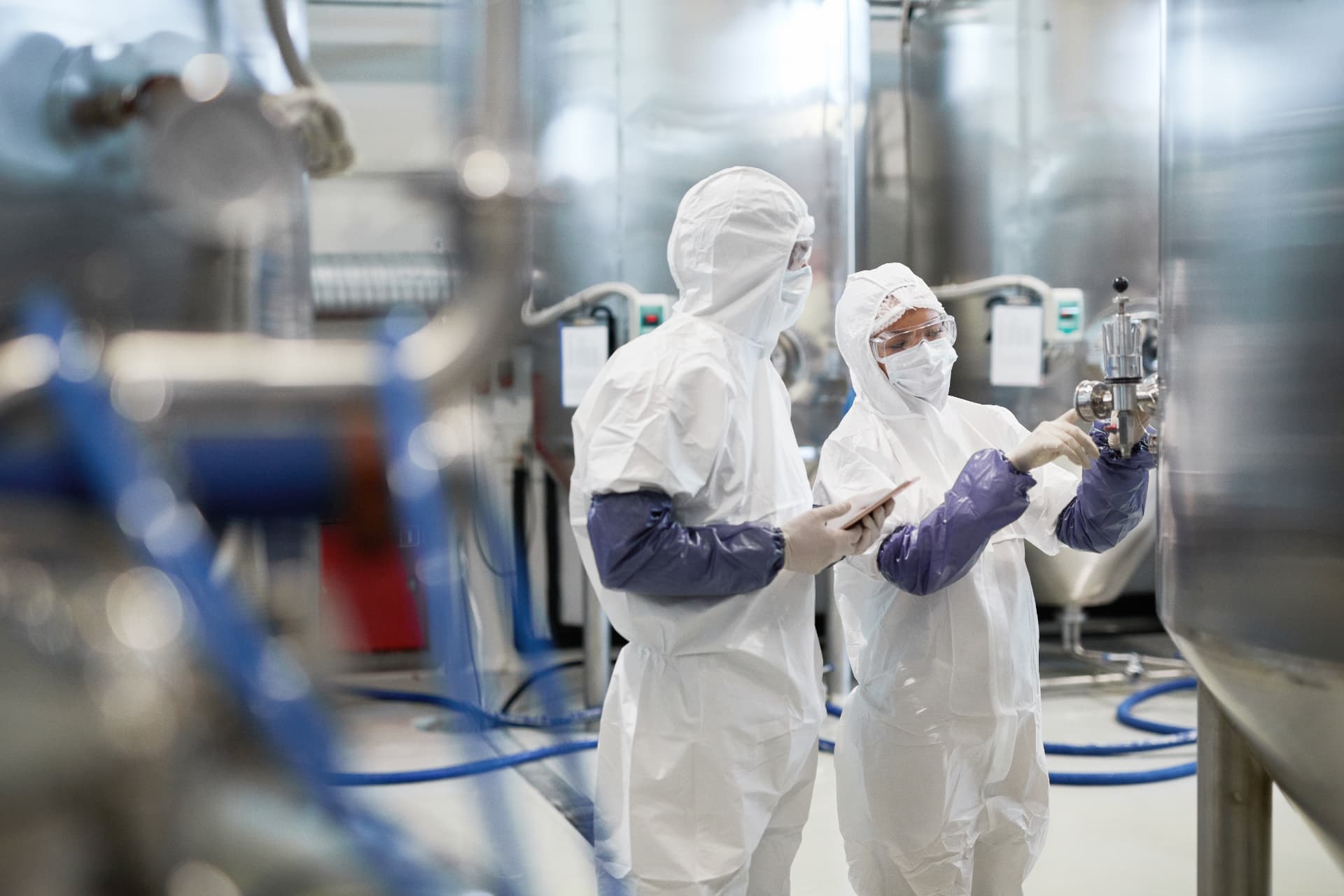 Technicians in clean suits inspecting equipment at an industrial plant Technicians in clean suits inspecting equipment at an industrial plant
