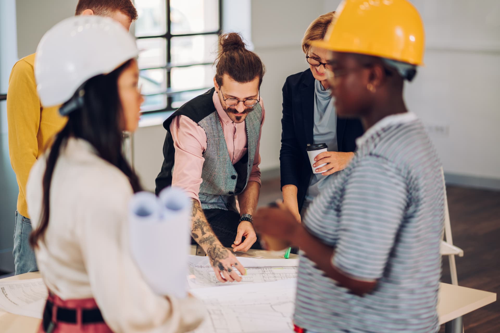 Business colleagues reviewing blueprints together at a table Business colleagues reviewing blueprints together at a table