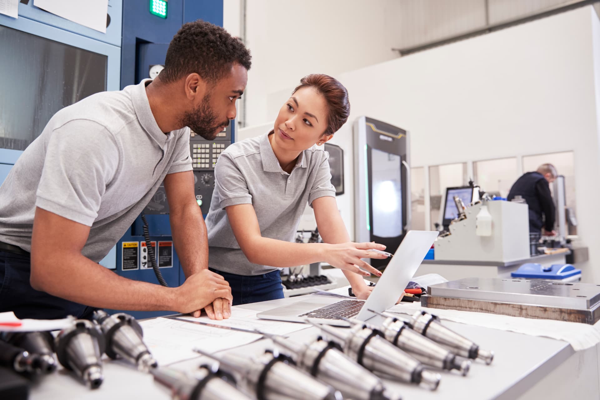 Accountability Rhythms That Outlast the Initiative Two engineers reviewing plans at a laptop on a modern plant floor